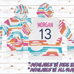May include: White hoodie with a colorful abstract pattern. The back of the hoodie has the name "MORGAN" and the number "13" in navy blue.
