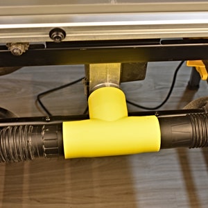 May include: A yellow plastic dust collection adapter with two black hoses attached to it. The adapter is connected to a table saw.