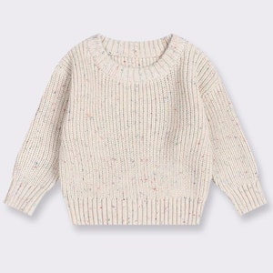 May include: A cream-colored knitted sweater with a speckled pattern. The sweater has long sleeves and a round neckline.