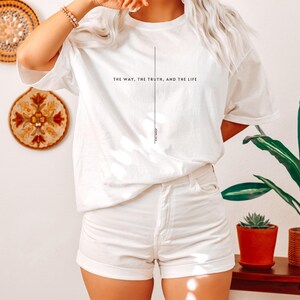 May include: White t-shirt with the text "The way, the truth, and the life" and a vertical line down the centre. The text "John 14:6" is at the bottom of the line.