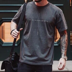 May include: A dark grey t-shirt with the text "The way, the truth, and the life" printed on the front.
