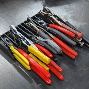 May include: A black plastic tool organizer with a variety of pliers, including needle-nose pliers, wire cutters, and adjustable pliers. The pliers are arranged in rows and are mostly black with red and yellow handles.