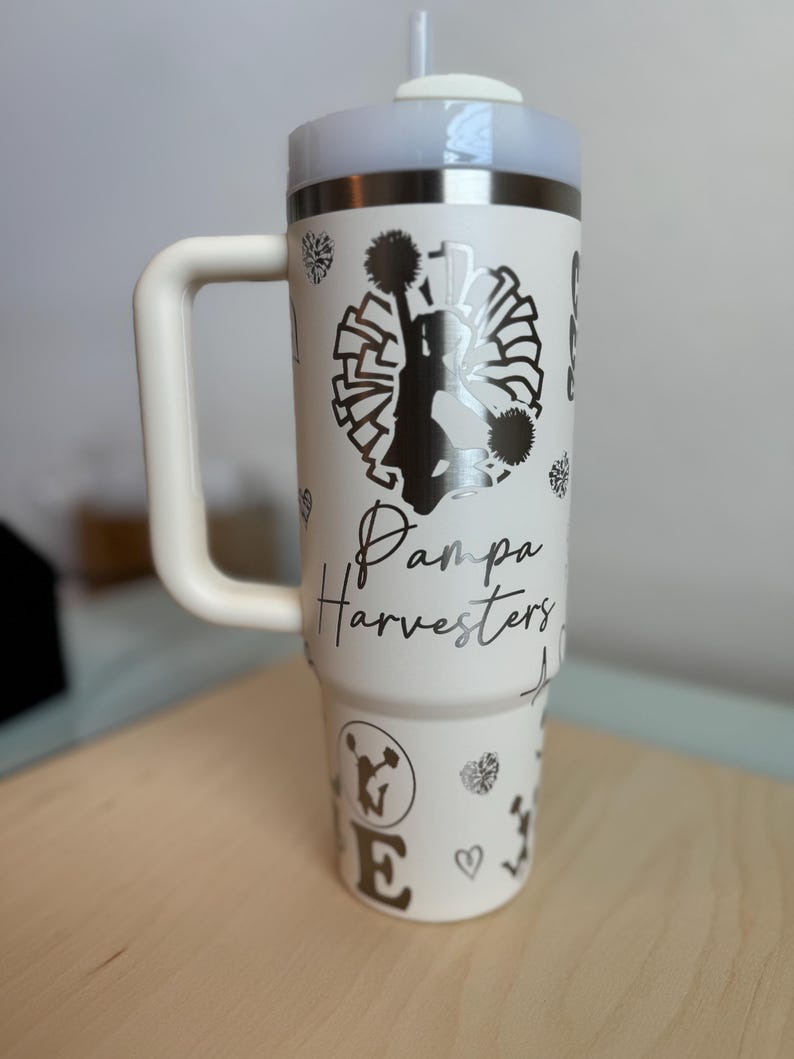 May include: White stainless steel travel mug with a black and white cheerleader graphic, the text "Pampa Harvesters", and a black and white pom-pom design.