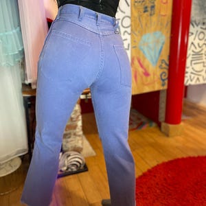 May include: Light blue denim jeans with a high waist and a slight flare at the ankle. The jeans have a faded, ombre effect, transitioning from light blue to a darker shade at the hem. The jeans have classic five-pocket styling.