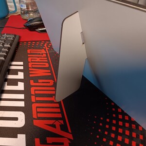 May include: A white stand with a fold-out design. The stand is made of a sturdy material and has a smooth finish.