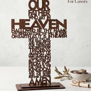 May include: A wooden cross with the Lord's Prayer cut out in the shape of the cross. The cross is brown and stands on a rectangular base. The words "Step by Step VIDEO", "For Lasers", and "SVG & Lightburn" are at the top and bottom.