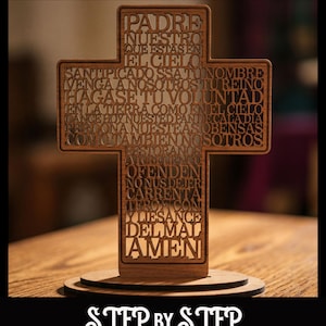 Puede incluir: Una cruz de madera con la oración del Padre Nuestro grabada en español. La cruz es de color marrón y se apoya sobre una base redonda. El texto "SVG & Lightburn" y "STEP BY STEP VIDEO" también está presente.