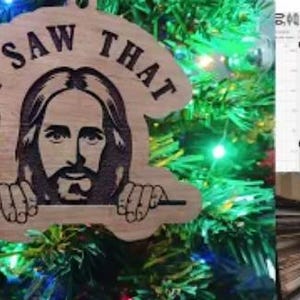 May include: Wooden Christmas ornament with the phrase "I SAW THAT" and an image of Jesus. The ornament is hanging on a Christmas tree with blue and green lights. The ornament is made of light brown wood.