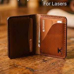 Op de afbeelding: Open bruin leren portemonnee met kaartsleuven. De portemonnee is open en toont een creditcard en de tekst "Step by Step VIDEO For Lasers" en "SVG & Lightburn". De portemonnee heeft een gestikte rand.