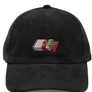 May include: Black corduroy baseball cap with an embroidered design of a cigarette pack. The pack is red, white, and gray, with cigarettes visible. The cap has a curved brim and an adjustable strap.