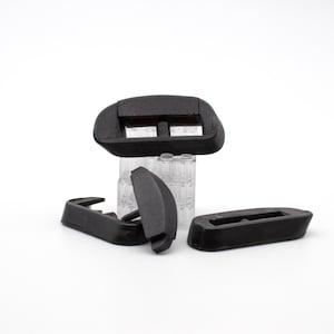 May include: Four black plastic buckles, two are rectangular with a slot in the middle, one is a half-circle shape, and the other is a curved shape.