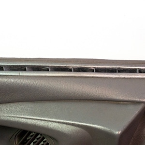 Może przedstawiać: Zbliżenie na szare wnętrze samochodu z srebrnym nawiewem. Nawiew ma wiele szczelin, przez które może przepływać powietrze.