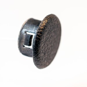 Może przedstawiać: Czarny plastikowy zatrzask z teksturą.