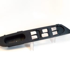 Może przedstawiać: Czarny plastikowy panel przełączników szyb samochodowych z czterema przyciskami i jednym przełącznikiem. Panel jest zaprojektowany do montażu w drzwiach samochodu.