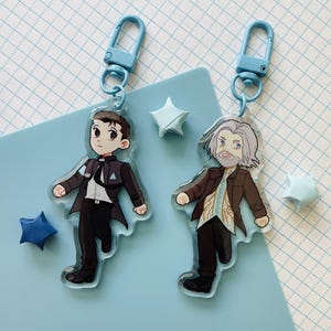 May include: A white ceramic mug with a black handle and the text "But First, Coffee" in a bold, black font. The mug is set against a neutral background, highlighting its simple design.