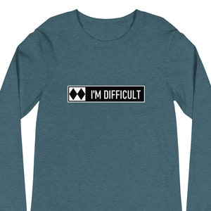May include: A teal blue long-sleeved shirt with a black rectangle and white text that reads "I'M DIFFICULT" and a black diamond symbol.