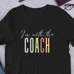 Camiseta Eu estou com o treinador Camiseta da esposa do treinador Camiseta colorida moderna da esposa do treinador Camiseta fofa Luzes de sexta à noite Design esportivo Eu amo o treinador