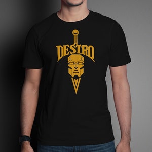 May include: A black t-shirt featuring a gold graphic of a sword and a masked face with the word "DESTRO" above it.