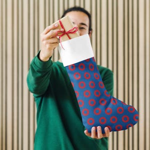 May include: A blue and red Christmas stocking with a donut pattern. The stocking is filled with a wrapped gift.