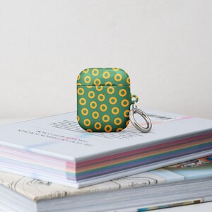 Peut inclure: Une coque pour Airpods verte et jaune avec un motif de beignets et un porte-cl&eacute;s argent&eacute;.