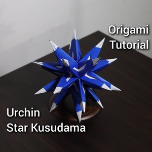 Op de afbeelding: Een blauwe en witte origami-zee-egelster-kusudama, een traditionele Japanse papierkunst. De ster is gemaakt van veel gevouwen papieren eenheden en is een populair origami-model.