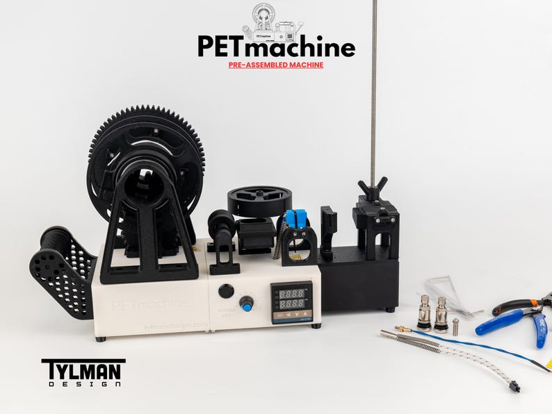 K&ouml;nnte beinhalten: Eine vormontierte PETmachine von Tylman Design mit wei&szlig;er Basis, gro&szlig;em schwarzen Zahnrad, digitalem Temperaturregler und verschiedenen mechanischen Komponenten. Enthalten sind Metalld&uuml;sen, blaue und silberne Dr&auml;hte sowie eine Zange.