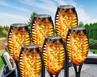 May include: Six solar powered flickering flame lights with black metal cages and a decorative design. The lights are on stakes and are arranged in a semi-circle.