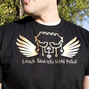 May include: Black t-shirt with a gold design featuring a castle, wings, and the text "Lirach Tasa Vefa Wehl Belial".