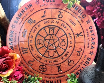 May include: A round wooden disc with a pentagram in the center and a circle around it with the names of the eight pagan holidays and the zodiac signs. The disc is painted in shades of orange and brown.