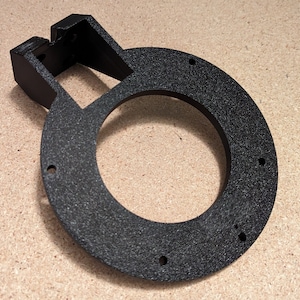 Pode incluir: Suporte de anel impresso em 3D de plástico preto com uma base retangular e vários orifícios.