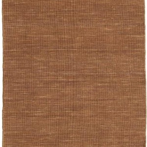 May include: A rectangular brown rug with a woven texture. The rug has a natural, earthy tone and a simple, yet elegant design. The weave pattern creates a subtle grid-like effect.