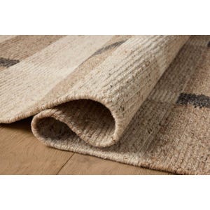 Peut inclure: Un tapis rectangulaire enroulé avec une texture tissée naturelle. Le tapis présente des rayures alternées beiges, beiges et gris foncé. Le bord du tapis est visible, montrant son épaisseur et sa construction.