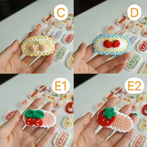 May include: Handmade crochet hair clips in various fruit designs, including cherries and strawberries. Each clip features a rectangular shape with a decorative border and colorful fruit accents. The clips are small, measuring approximately 2 inches in length.