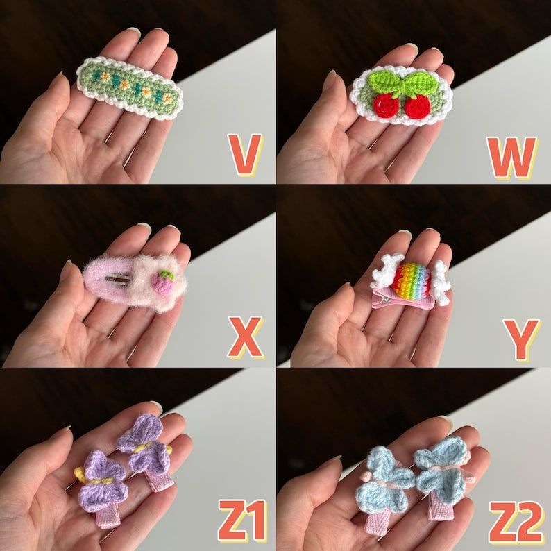 May include: A collection of handmade hair clips in various designs. The clips include a green and white floral design, red cherries, a pink strawberry, a rainbow candy, and purple and blue flower designs. Each clip is held in a hand.