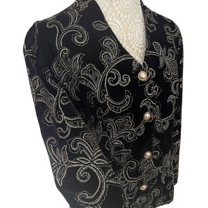 May include: A black velvet blazer with a paisley pattern embroidered in gold sequins. The blazer has a v-neck and a button closure.