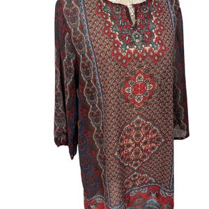 May include: A red, blue and white patterned tunic with a V-neck and 3/4 sleeves.