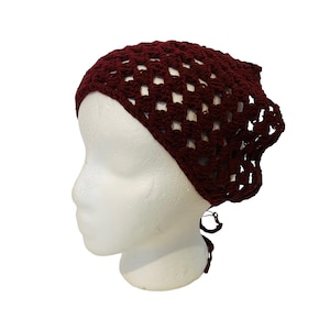 May include: A burgundy crocheted hair scarf with a square pattern and a tie at the back.