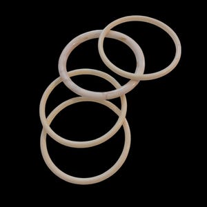 May include: A set of three circular bangles in a smooth, off-white, cream-coloured material. The bangles are arranged in an overlapping, cascading formation, showcasing a simple, rounded profile and a consistent, polished finish throughout.