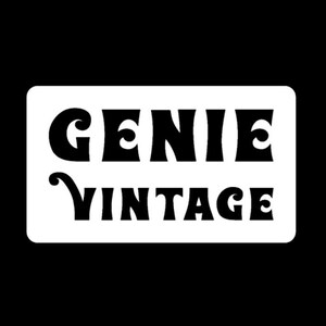 May include: A white rectangular sign with rounded corners, featuring the words "GENIE VINTAGE" in bold, black, retro-style lettering. The background is solid black, creating a high-contrast design.