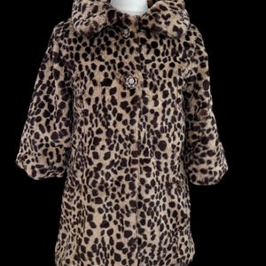 May include: A faux fur coat featuring a tan and brown leopard print pattern. The coat has a wide collar, three-quarter length sleeves, and two decorative circular buttons with a metallic finish down the centre front closure.