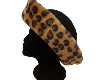 May include: A black beret with a faux fur leopard print band. The band features a tan background with dark brown spots. The beret is displayed on a black mannequin head against a white background.