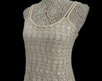 May include: A white crocheted tank top with a delicate floral pattern. The top has a scoop neck and thin straps.