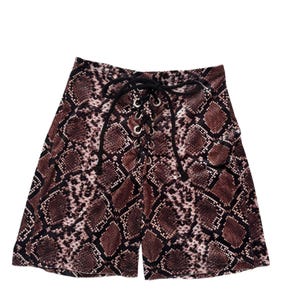 May include: High-waisted shorts featuring a brown and black snakeskin print pattern. The front centre includes a vertical lace-up detail with silver-toned metal grommets and black cord laces tied in a bow at the top of the waistband.