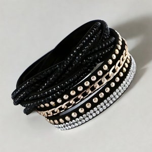 Puede incluir: Pulsera de cuero negro con cadena dorada y pedrería transparente y negra.
