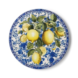 Op de afbeelding: Ronde decoratieve plaat met een citroenboomontwerp. De plaat heeft een witte achtergrond met blauwe bloempatronen en een blauwe rand. De citroenen zijn geel met groene bladeren.