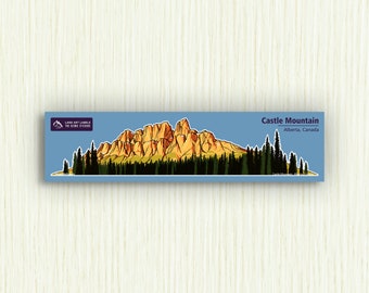 Puede incluir: Una pegatina azul y amarilla con una ilustración de dibujos animados de Castle Mountain en Alberta, Canadá. El texto "Castle Mountain, Alberta, Canadá" está impreso en la pegatina.