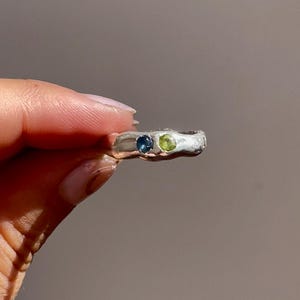 May include: A silver ring with a blue and green gemstone set in the band.