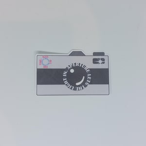 Aperture lets the light in / Autocollant en forme d'appareil photo APERTURE