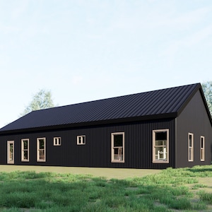 Op de afbeelding: Een modern huis met zwarte buitenmuren en een donker dak, voorzien van meerdere ramen. Het gebouw staat in een groene omgeving met bomen en een heldere blauwe lucht. De ramen hebben lichte kozijnen.