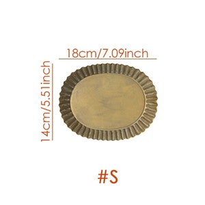 May include: A gold-colored, oval-shaped metal tray with a fluted edge. The tray measures 18 inches in length and 14 inches in width. The tray is labeled with the size "#S".